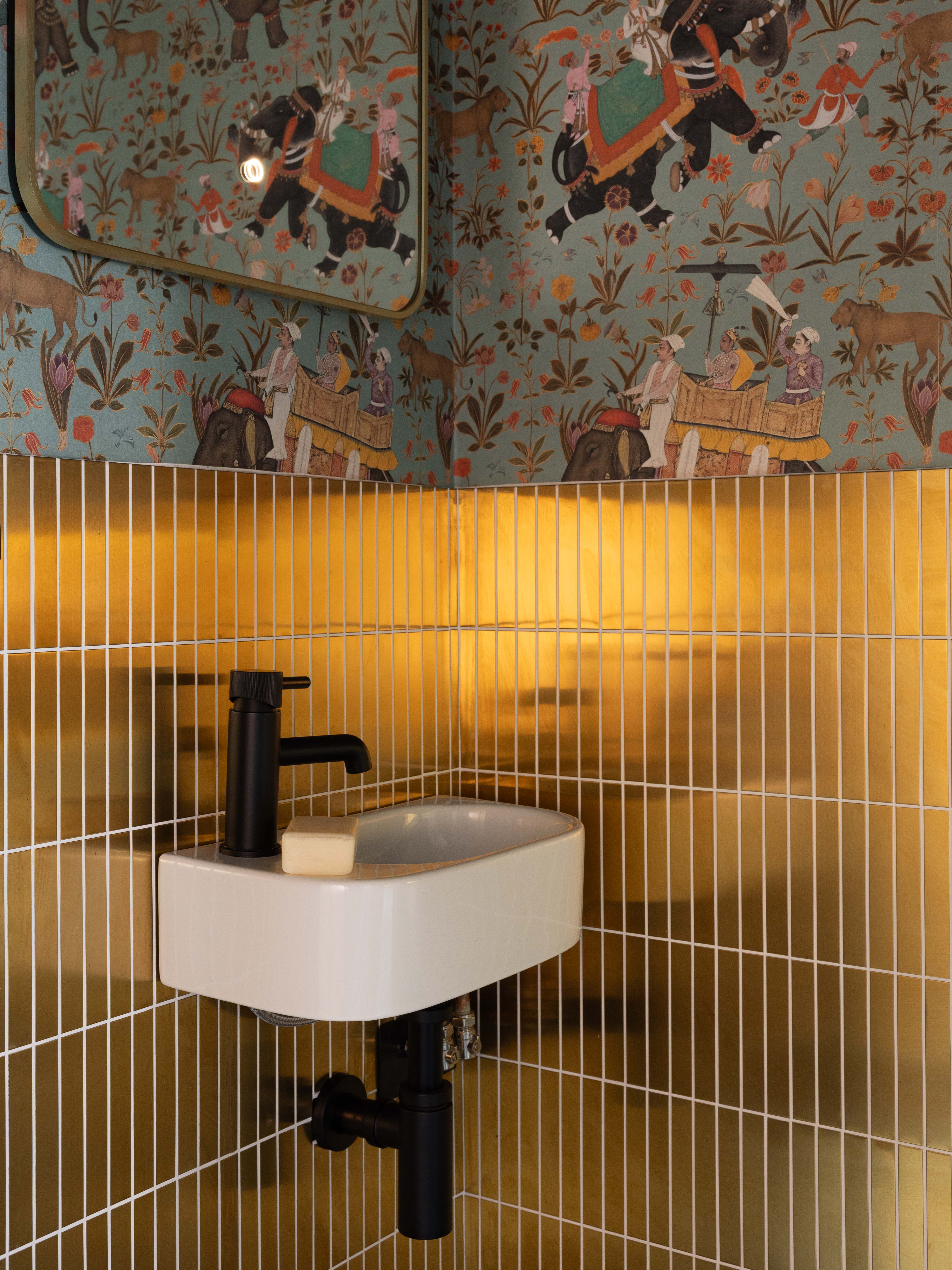 Powder room with patterned wallpaper and ochre tiles at Ewhurst Road